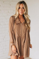 Woman wearing a brown dress against a white brick wall