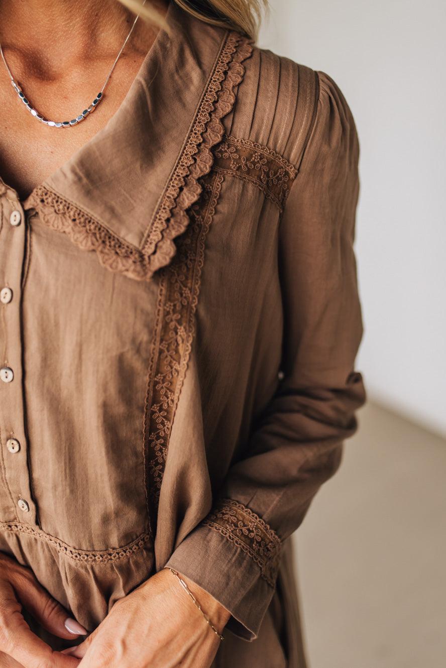 Brown dress with lace details worn by a person, against a neutral background