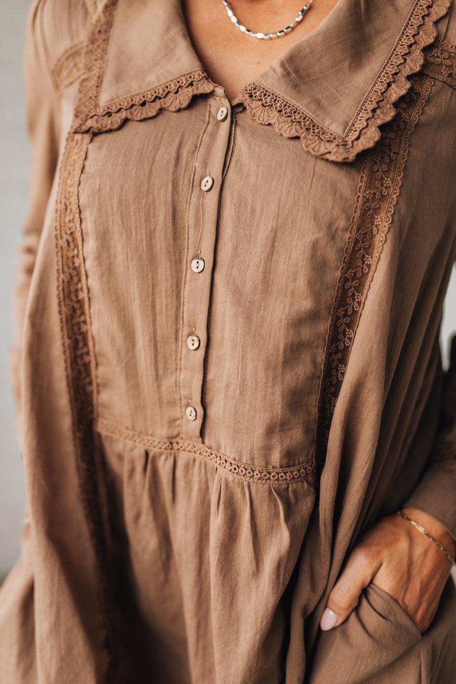 Close-up of a brown dress with lace details on a plain background