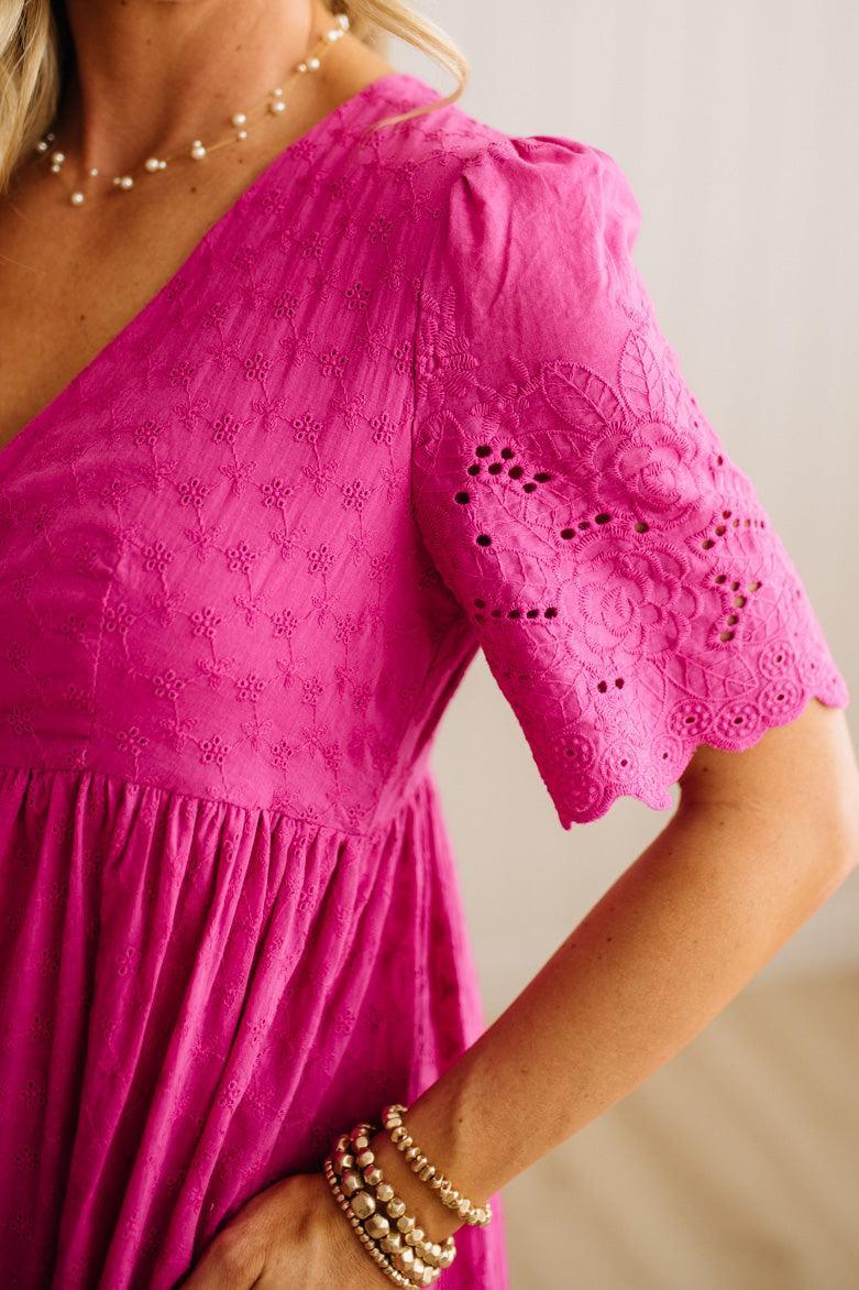 Close-up of a person wearing a bright pink dress with lace details.