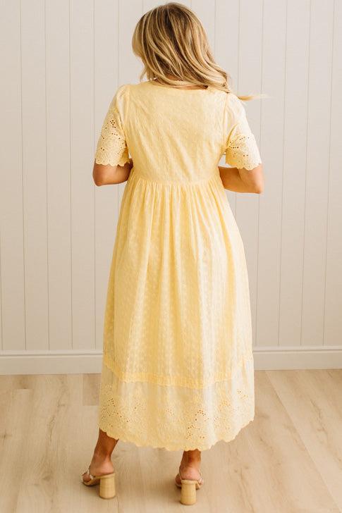 Woman wearing a yellow dress with lace details in a minimal indoor setting