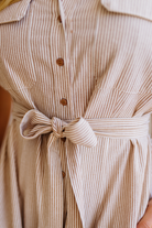 Close-up of a beige and brown striped dress with a tie waist.