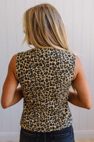Person wearing a leopard print sleeveless top with a neutral background