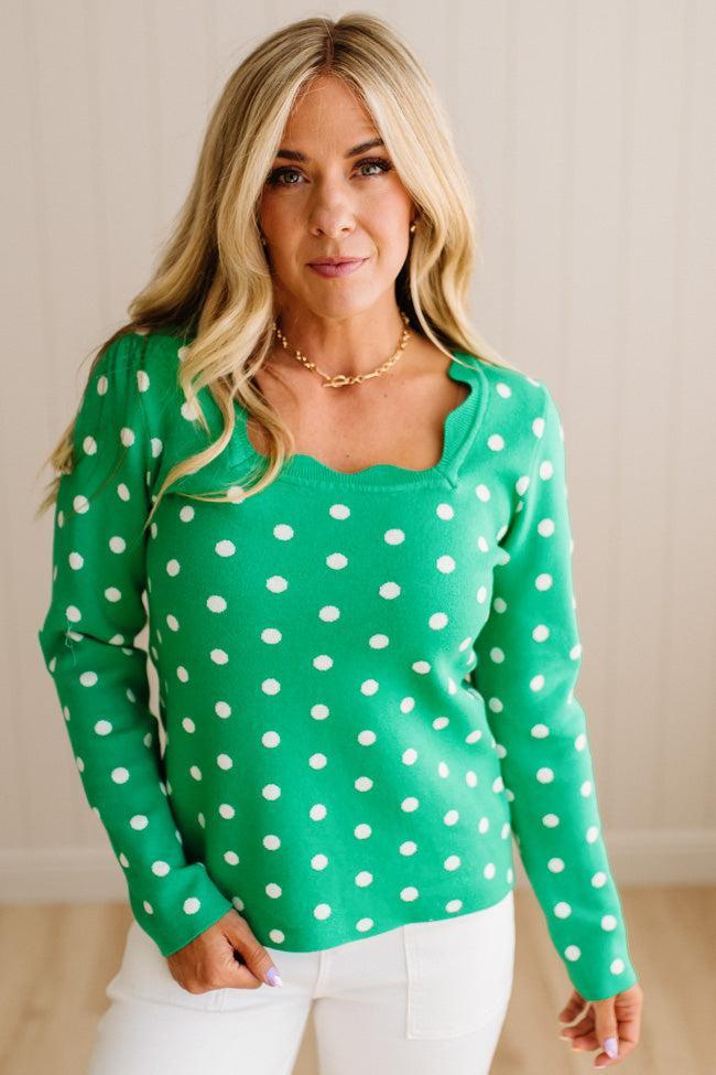Blonde woman wearing a long sleeve sweater with scalloped square neckline in green with white dots.