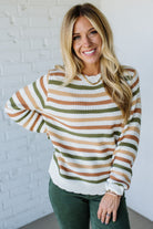 Woman wearing a striped sweater in front of a white brick wall