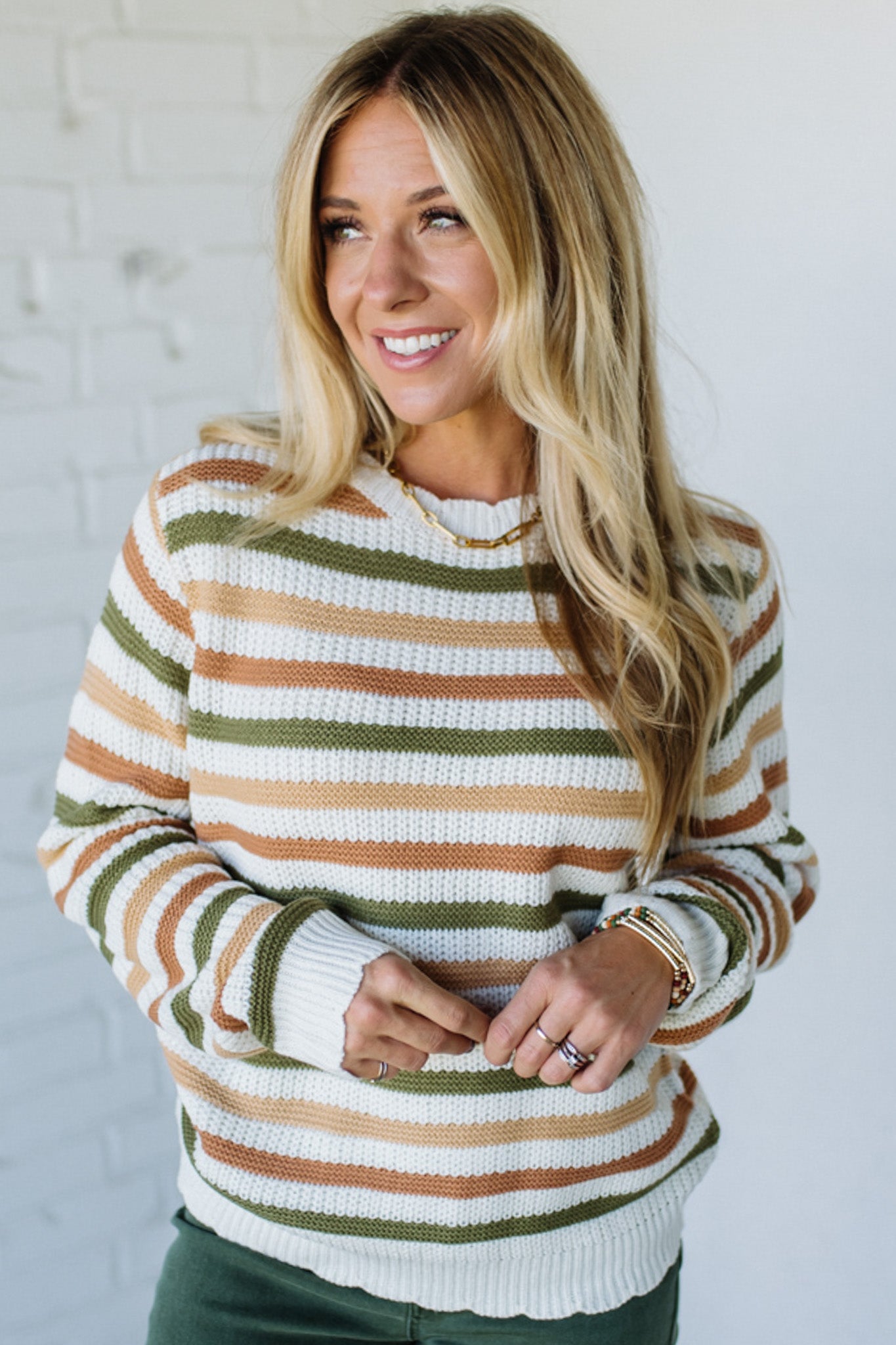 Woman wearing a striped sweater against a white brick wall