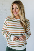 Woman wearing a striped sweater against a white brick wall