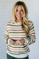 Woman wearing a striped sweater against a white brick wall