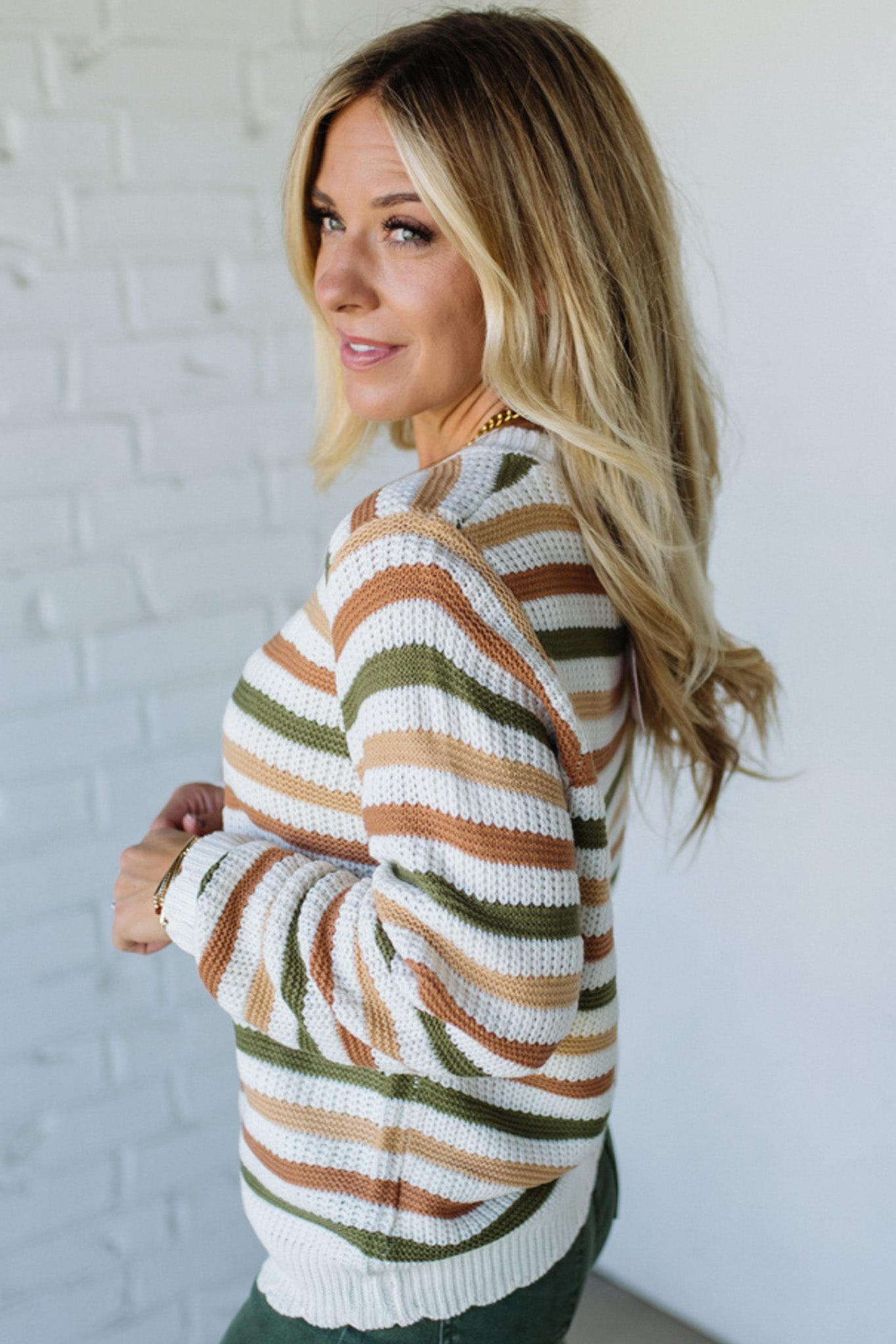 Woman wearing a striped sweater against a white brick wall