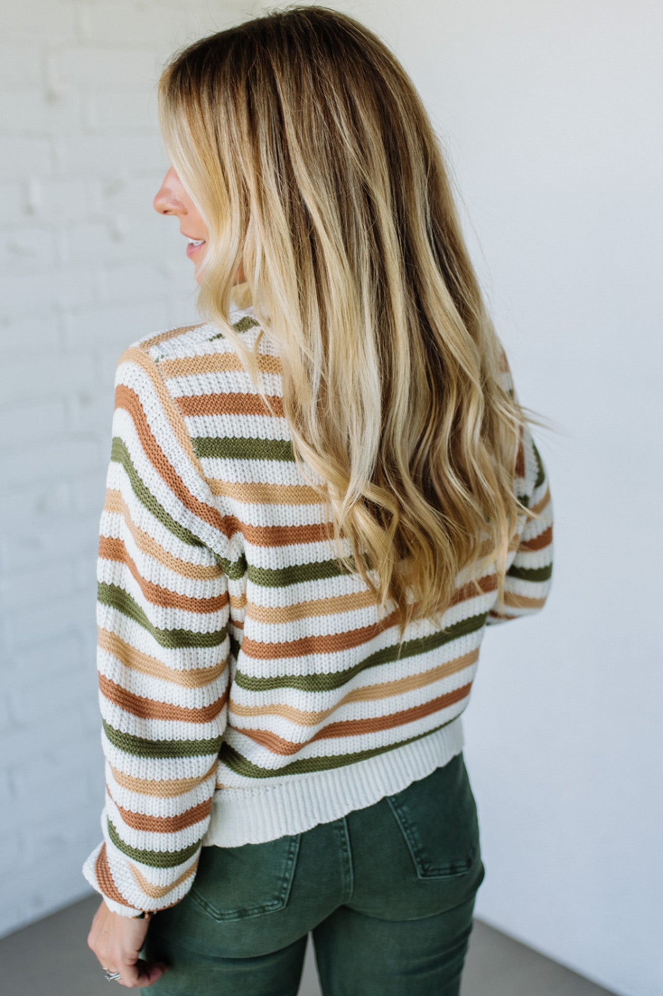 Woman wearing a striped sweater with a neutral background