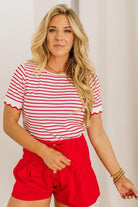 Woman wearing a red and white striped shirt and red shorts against a plain background