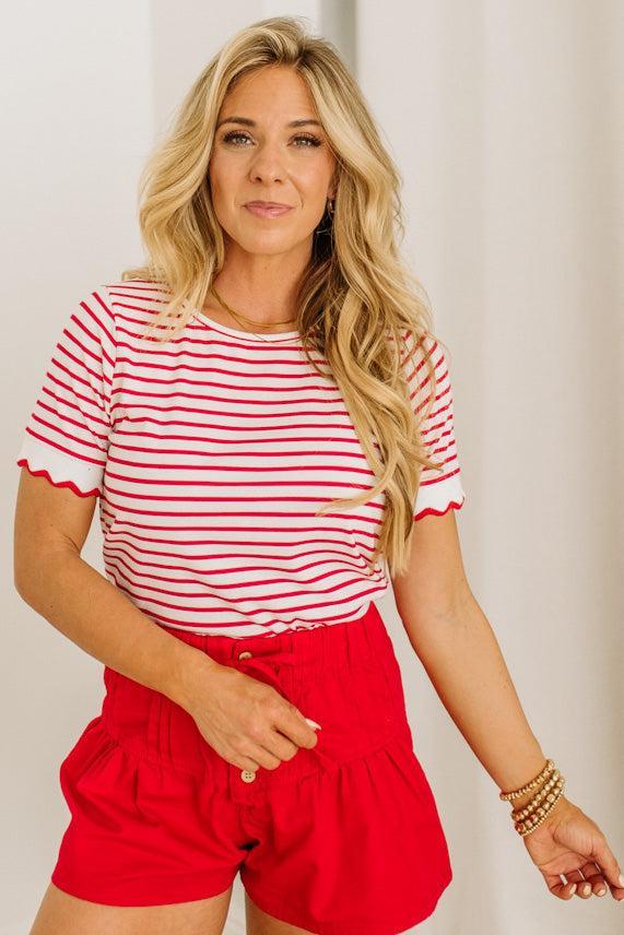 Woman wearing a red and white striped shirt and red shorts against a plain background