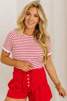 Woman wearing a red and white striped shirt and red shorts against a plain background