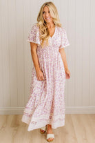 Woman wearing a floral dress standing against a white paneled wall.