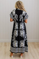 Woman wearing a black dress with white patterns in a minimal indoor setting