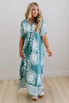 Woman wearing a teal dress with white patterns indoors.