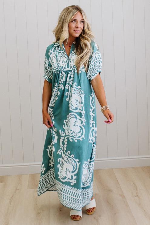 Woman wearing a teal dress with white patterns indoors.