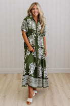 Woman wearing a green and white patterned dress standing against a plain background