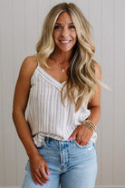 Woman wearing a striped tank top and jeans with a neutral background