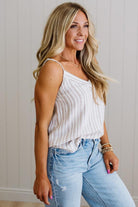 Woman wearing a white ribbed tank top and light blue jeans indoors.