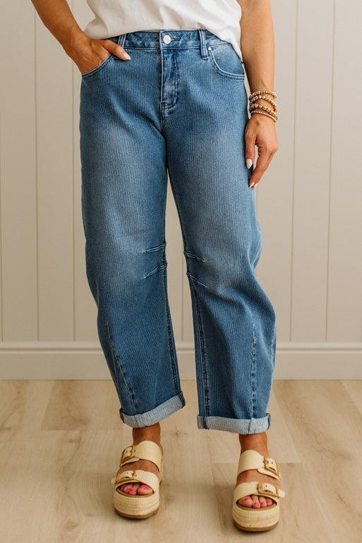 Person wearing blue jeans and sandals standing against a neutral background
