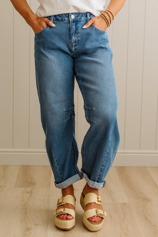 Person wearing blue jeans and sandals with a neutral background