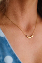 Gold necklace on a person with a blue garment in the background