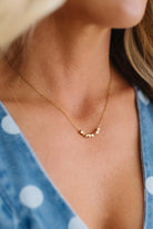 Close-up of a gold necklace on a person wearing a blue polka dot garment.