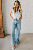 BLONDE WOMAN WEARING DRAWSTRING WAIST DETAIL STRETCH SIDE SLIT WIDE LEG JEAN IN MEDIUM BLUE.