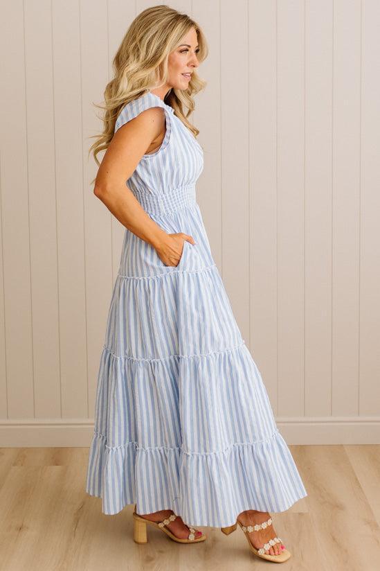 Woman wearing a blue and white striped dress against a beige wall.
