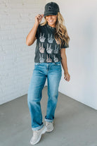 Woman wearing a graphic t-shirt, jeans, and a cap indoors.
