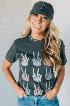 Woman wearing a dark gray t-shirt with hand sign prints and a matching cap.