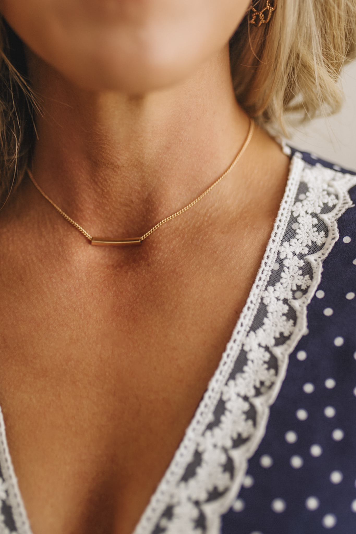 Close-up of a person wearing a gold necklace with a blurred background