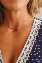 Close-up of a person wearing a gold necklace with a blurred background