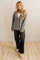 Blonde woman wearing a grey classic notched lapel sweater cardigan with tailored lines and patch pockets.