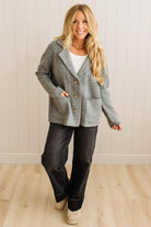 Blonde woman wearing a grey classic notched lapel sweater cardigan with tailored lines and patch pockets.