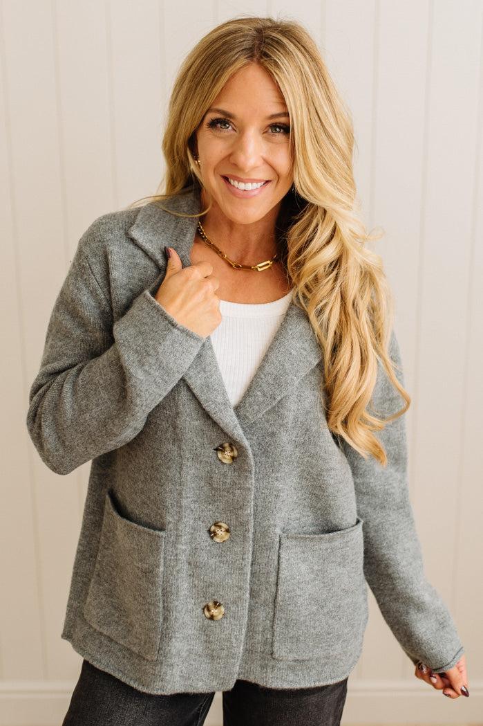 Blonde woman wearing a grey classic notched lapel sweater cardigan with tailored lines and patch pockets.