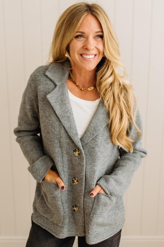 Blonde woman wearing a grey classic notched lapel sweater cardigan with tailored lines and patch pockets.