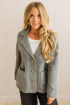 Blonde woman wearing a grey classic notched lapel sweater cardigan with tailored lines and patch pockets.