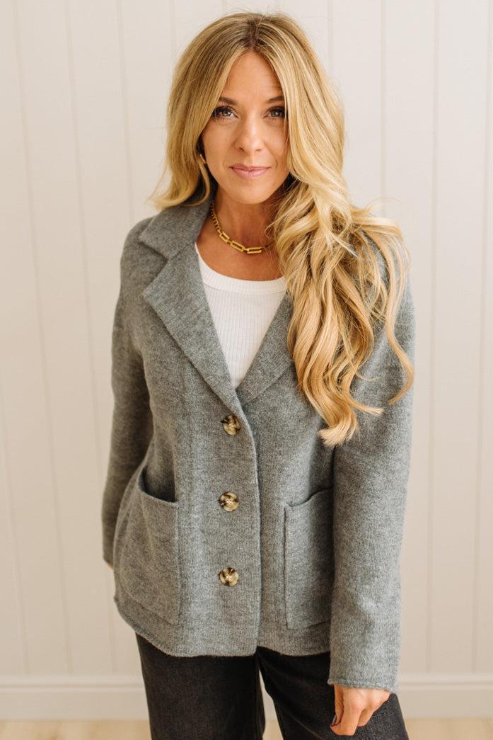 Blonde woman wearing a grey classic notched lapel sweater cardigan with tailored lines and patch pockets.