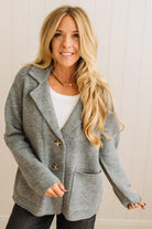 Blonde woman wearing a grey classic notched lapel sweater cardigan with tailored lines and patch pockets.