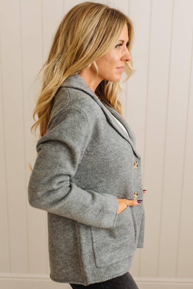 Blonde woman wearing a grey classic notched lapel sweater cardigan with tailored lines and patch pockets.