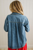 Person wearing a blue denim shirt with a neutral background