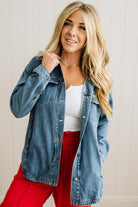 Woman wearing a denim jacket, white top, and red pants against a neutral background