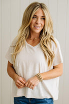 Woman wearing a sand beige t-shirt and blue jeans with a neutral background