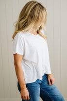 Person wearing a white t-shirt and blue jeans against a neutral background