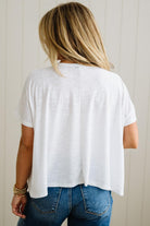 Person wearing a white t-shirt and blue jeans against a neutral background