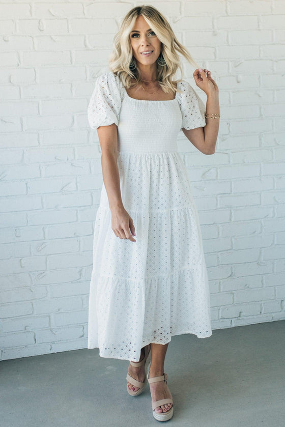 Woman wearing a white eyelet detail maxi dress with short sleeves and a smocked bodice