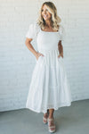 Woman wearing a white eyelet detail maxi dress with short sleeves and a smocked bodice
