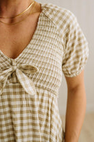 Woman wearing a checkered dress with a neutral background